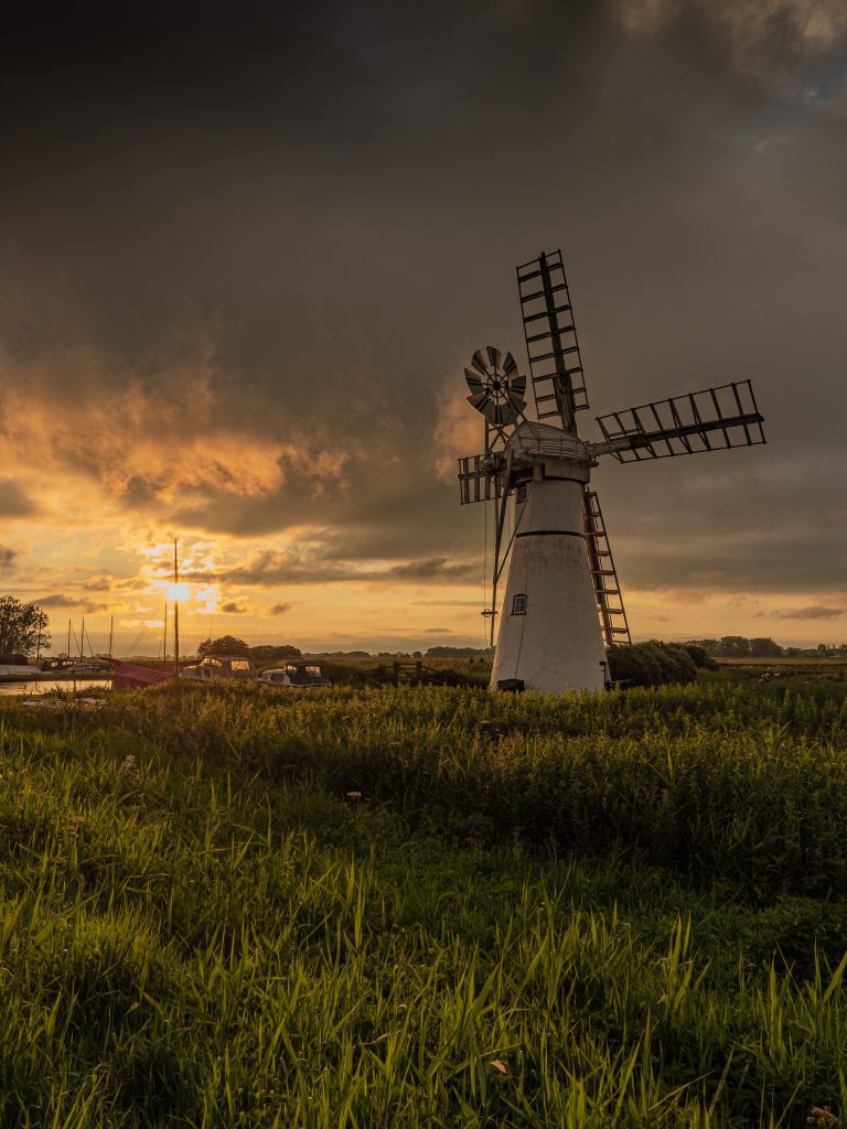 Photograph of Thurne Mill on the Norfolk Broads set against an angry stormy sky at sunset